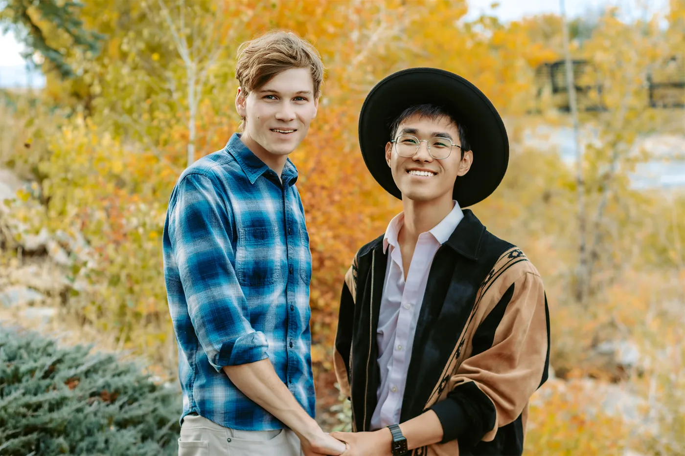 Jack and his husband Bo holding hands in front of fall leaves