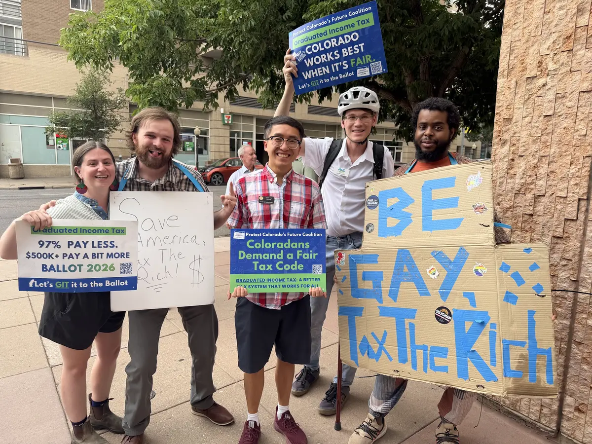 Jack and fellow volunteers holding signs for the graduated income tax, including one reading Be Gay, Tax the Rich