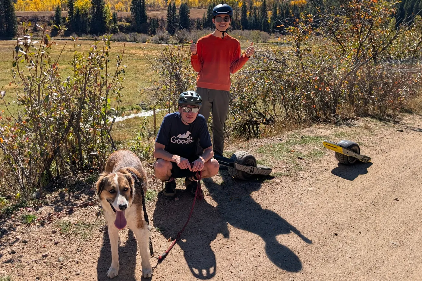 Jack and Bo riding onewheels on a trail with their dog, Cookie